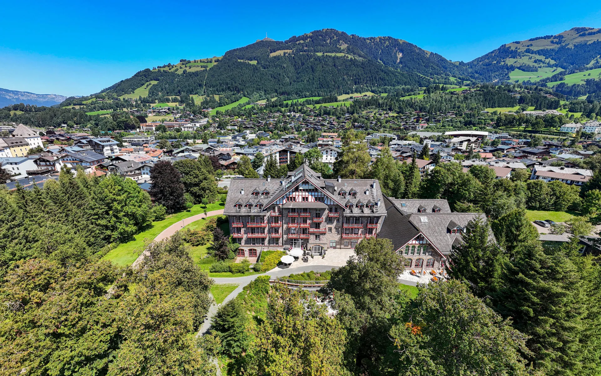Aerial view of Grandhotel surrounded by greenery and mountains.