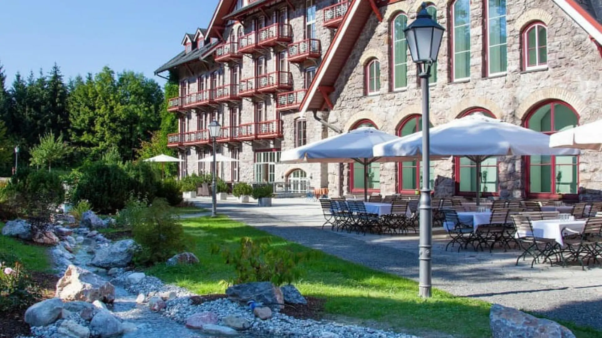 Exterior view of Grand Hotel Kitzbühel with a pond and lush greenery