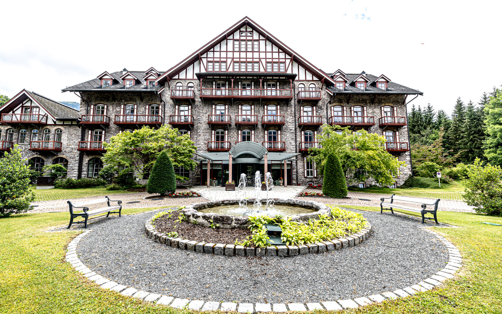 Historic building with a fountain and landscaped garden in front.