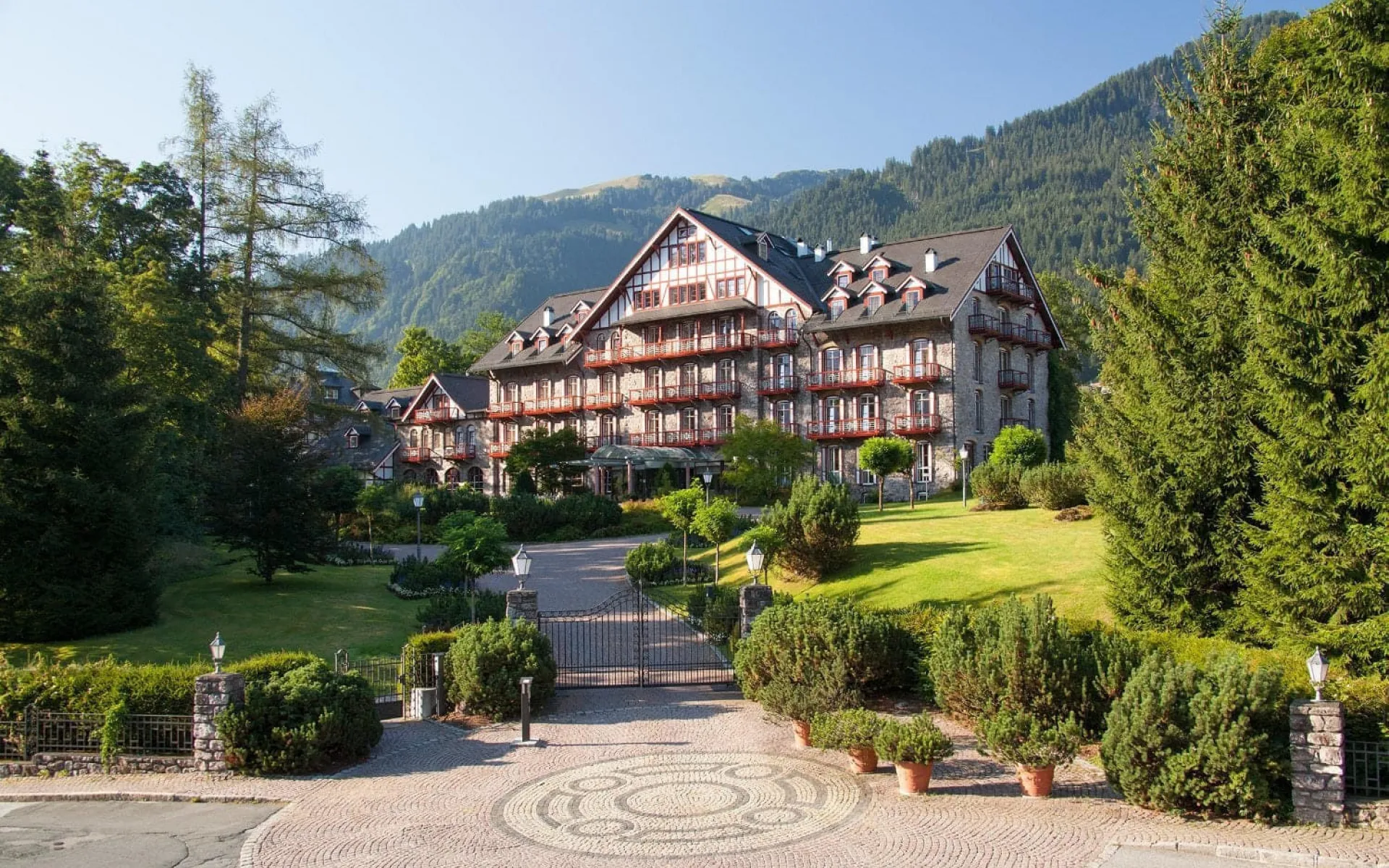 Grand Hotel Kitzbühel with garden and mountain landscape in the background